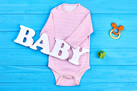 High quality natural bodysuit for baby-girl. Infant baby striped cotton bodysuit, accessories, blue wooden background. Infant baby clothes and accessories background.の写真素材
