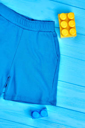Baby-boy cotton shorts, top view. High quality casual shorts for toddler boy, blue wooden background. Textile clothes for kids.の写真素材
