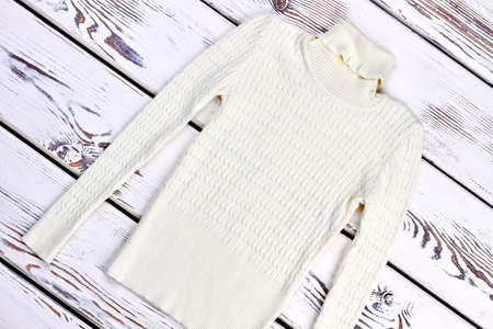 White warm winter sweater. Turtle neck knitted sweater with a beautiful ornament. New beautiful sweater on vintage wooden background.の写真素材