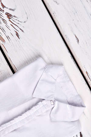 White female shirt, top view. Girls white cotton blouse folded on old wooden background. High quality fabric white woman blouse.の写真素材