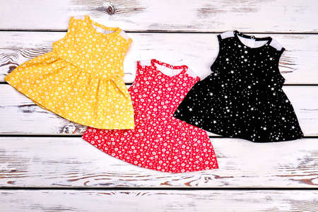Set of beautiful dresses for newborn girls. Collection of new printed tops for infant girls, top view.の写真素材