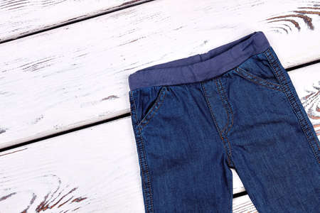 Kids denim pants, top view. Childs jeans on white wooden background. High quality kids apparel.の写真素材