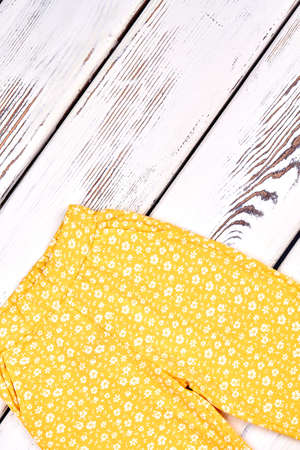 Baby-girl vintage print trousers. Toddler girl brand summer breeches on white wooden background, top view. Kids summer fashion.の写真素材