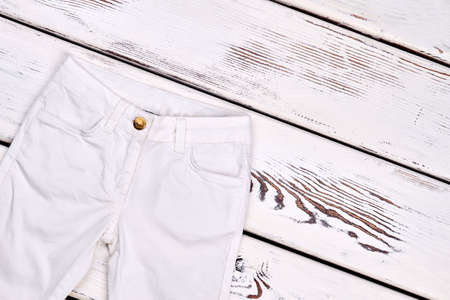 Childrens white denim trousers isolated. Girls high quality brand pants on old wooden background.の写真素材