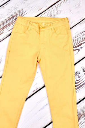 Young woman middle waist trousers. Yellow cotton pants for girls on old wooden background. Female summer outfit.の写真素材