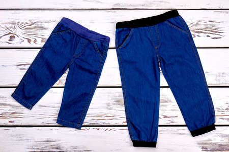 New jeans for infant and toddler kids. Kids high quality jean trousers on white wooden background. Childs fashion apparel on sale.の写真素材
