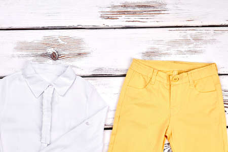 Teenage girls elegant outfit. Young girl white blouse and skinny colored trousers on white wooden background. Girls classic outfit.の写真素材