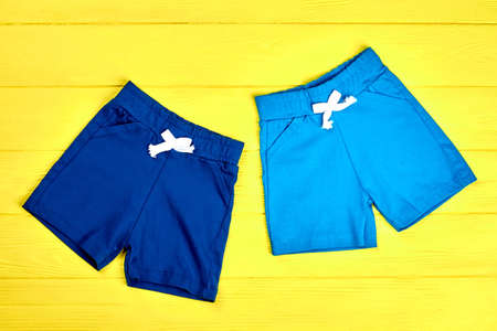 Toddler boys textile colored shorts. Set of new summer sorts for baby boys on yellow wooden background. Shop online kids summer garment.の写真素材