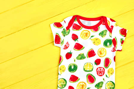 Newborn child beautiful summer romper. Baby short sleeve bodysuit on yellow wooden background. Hot...