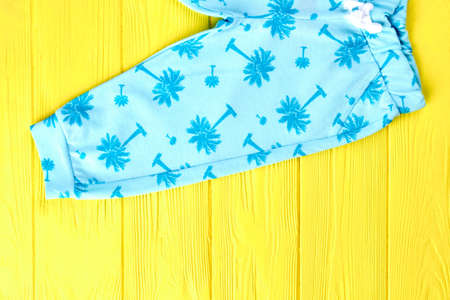 Infants cute blue printed trousers. Babies boutique clothing on yellow wooden background. Childs fashion outfit.の写真素材