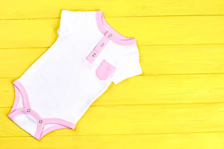 Baby white and pink summer romper. Infant girls cute cotton bodysuit on colored wooden background, top view. Hot sale of infants brand outfit.の写真素材
