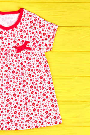 Infant girl new printed sundress. Little girl casual patterned dress on yellow wooden background. Kids natural apparel.の写真素材