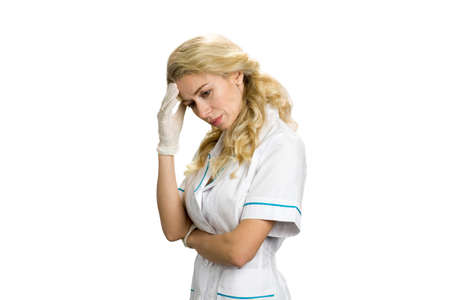 Thinking nurse on white background. Young female doctor looking thoughtful on white background. Worried young female doctor.の写真素材