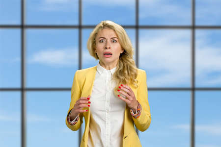 Shocked and frustrated business woman. Shocked business woman looking horrified standing on office window background.の写真素材