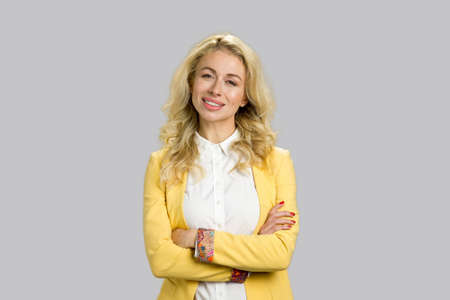 Portrait of smiling young woman. Attractive european young woman wearing formal wear crossed arms standing on grey background.の写真素材