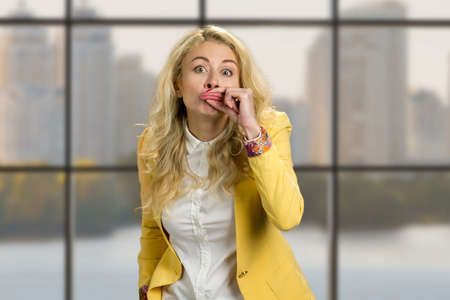 Young woman making funny lips. Young business woman making funny grimace with her lips standing on business center window background.の写真素材