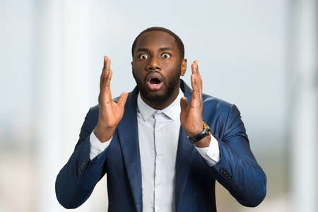 Surprised afro american businessman. Young confident man with wide opened eyes and mouth. Human feelings of surprise.の写真素材