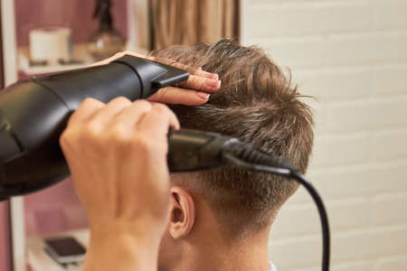 Barber drying hair close up. Work of hairstylist with client. Hair dryers recommended by stylists.の写真素材