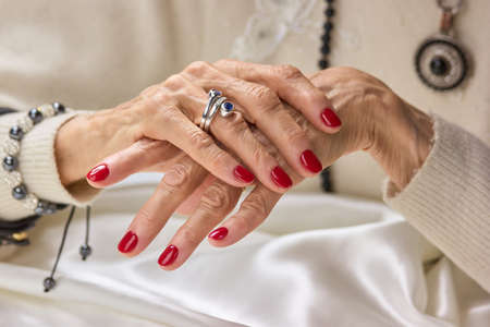 Luxury female hands with red manicure. Aged woman manicured hands with beautiful silver ring. Senior...