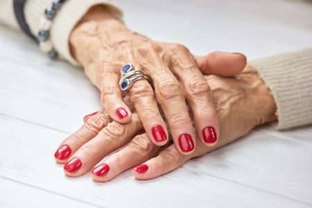 Woman manicured hands on table. Female aged hands with perfect red nails and silver luxury ring.の写真素材