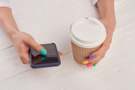Female manicured hands with smartphone. Woman hand with colorful nails holding touch screen phone...