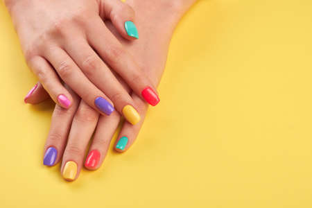 Female hands with summer manicure. Teen girl hands with bright summer manicure on yellow background, copy space.の写真素材