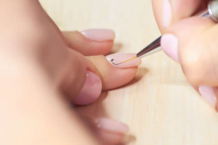 Process of receiving manicure in beauty salon. Manicurist doing design on female nails. Woman having maniure in beauty salon.の写真素材