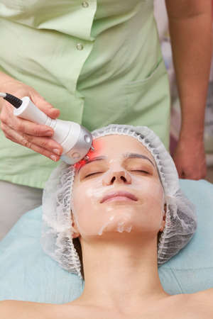 Female face, rf skin tightening. Young woman in facial mask.