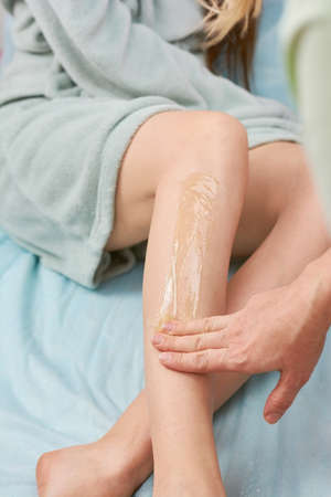 Leg sugaring, hand of cosmetician. Epilation in beauty clinic.の写真素材