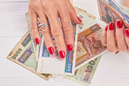 Manicured hands holding paper money of Myanmar. Senior woman hands with luxury red manicure. Well-groomed hands and Burma money.の写真素材