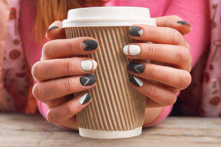 Manicured hands holding cardboard cup. Female hands with perfect manicure holding disposable cup of coffee. Time for beauty and relax.の写真素材