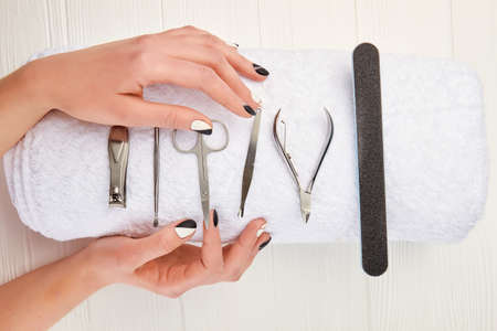 Manicured hands and equipment for manicure. Young woman hands with beautiful manicure on white towel with instruments for manicure. nails salon and spa.の写真素材