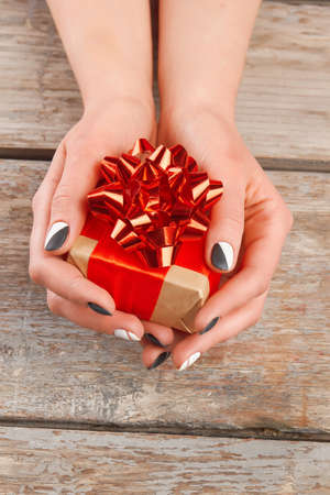 Manicured hands holding little gift box. Young woman hands with beautiful manicure and gift box, old...