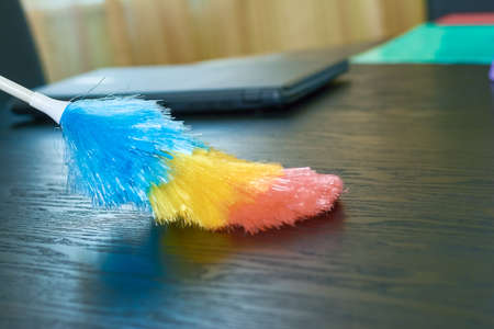 Colorful duster close up. Dust brush and wooden table. Office cleaning services.