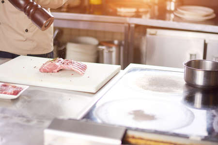 Chef processing ribs with spices. Male chef preparing pork ribs at professional kitchen. European delicious food.の写真素材