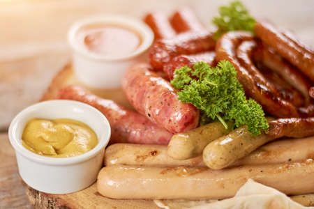 Grilled sausages with parsley and mustard. Appetizing assortment of grilled sausages with mustard and parsley. Delicious restaurant food.の写真素材