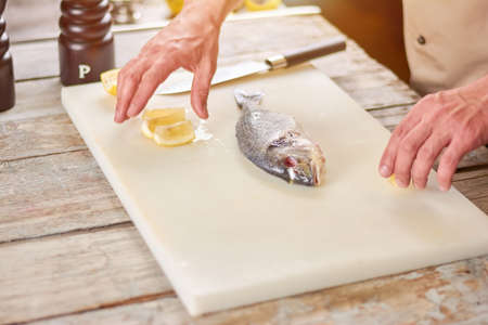 Preparation of a dorado grill. Fresh raw fish and lemon on cutting board. Cooking dorado fish.の写真素材