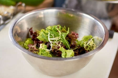 Mixed salad leaves in stainless bowl. Fresh mix of green and purple salad on table close up. Dish cooking at restaurant.の写真素材