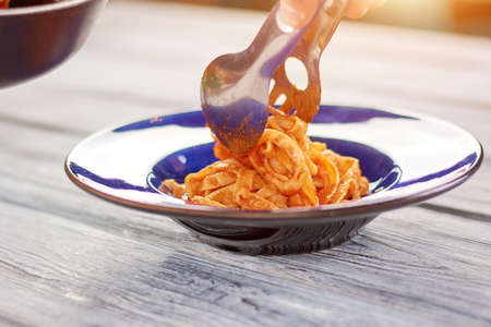 Kitchen stainless tongs putting pasta on plate. Appetizing pasta frutti di mare. Culinary and italian food.の写真素材