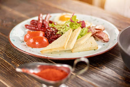 English breakfast on plate. English breakfast with toasts, tomatoes, beans, fried eggs, baked sausages and bakon. English breakfast in restaurant.の写真素材