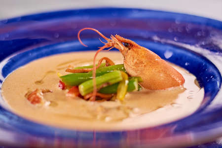 Cream soup with crayfish tails and vegetables. Tasty soup puree with vegetables and crayfish. Delicious dinner on plate close up.の写真素材