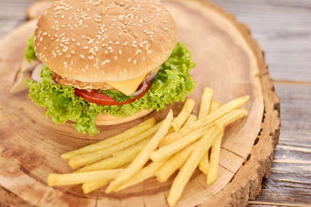 Fresh tasty burger and french fries. French fries and appetizing cheeseburger on natural wood....