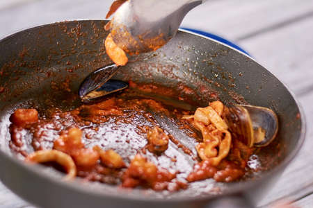 Cooking italian pasta with seafood. Delicious pasta with red sauce and mussels in frying pan.の写真素材