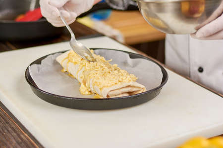 Chef putting cheese on burrito. Chef preparing mexican burrito at kitchen. Burrito in frying pan.の写真素材