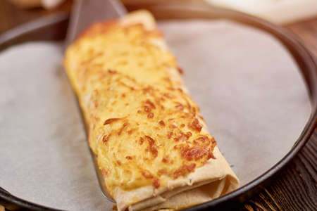 Appetizing burrito baked with cheese. Burrito cooking process. Mexican burrito wraps with meat, beans and vegetables in frying pan.の写真素材