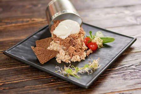 Appetizing dish on plate in restaurant. Pearl barley with dietetic meat, sauce, toasts, cherry tomatoes on wooden table. Delicious breakfast in restaurant.の写真素材