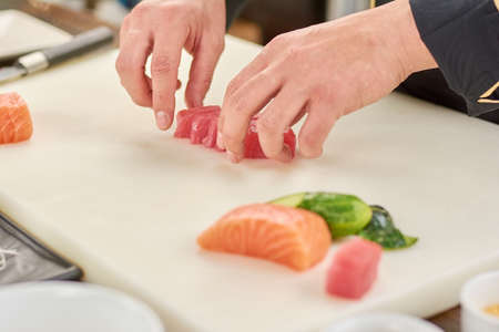 Chef sliced raw tuna fillet. The process of sushi making at professional kitchen. Cook at work, kitchen.の写真素材
