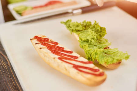 The process of long sandwich cooking. Preparing of classic hot dog at kitchen. Cooking and culinary concept.の写真素材