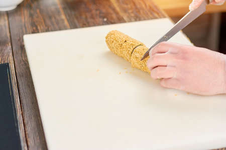 Chef hands with knife cutting sushi roll. Cook in gloves slicing long sushi roll in small pieces. Japanese chef at work, kitchen.の写真素材