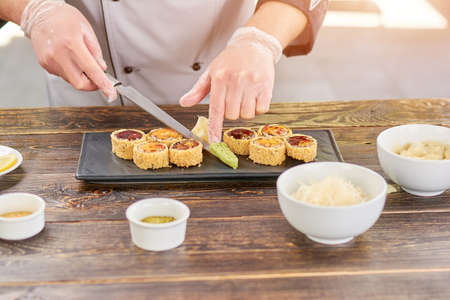 Chef serving sushi set with wasabi. Cook adding wasabi to sushi set on plate. Sushi preparation at kitchen.の写真素材